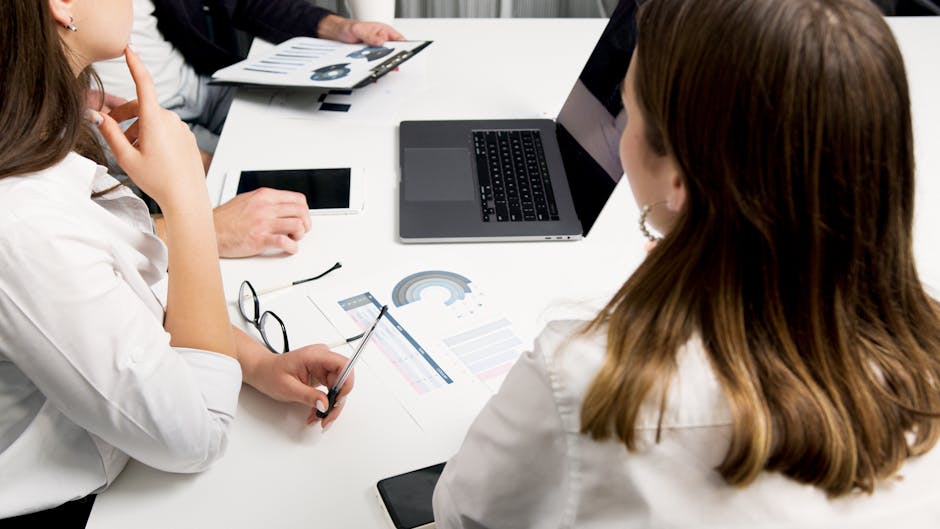 eam reviewing financial charts and data on laptops during a meeting at Frontline Collections – London Office (Debt Collection)