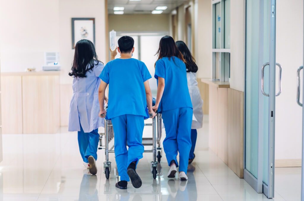 Medical staff pushing a patient bed down a hospital hallway.