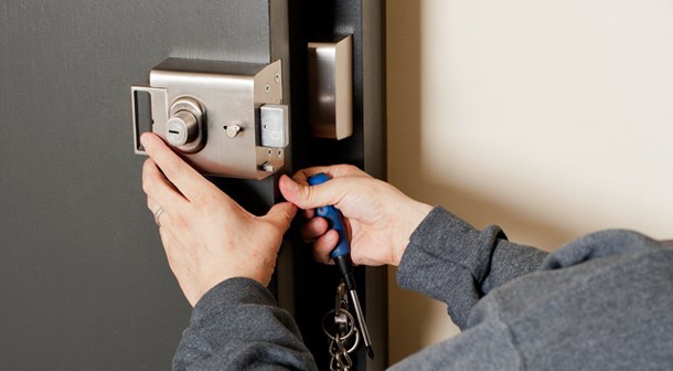 A locksmith installing or repairing a door lock.