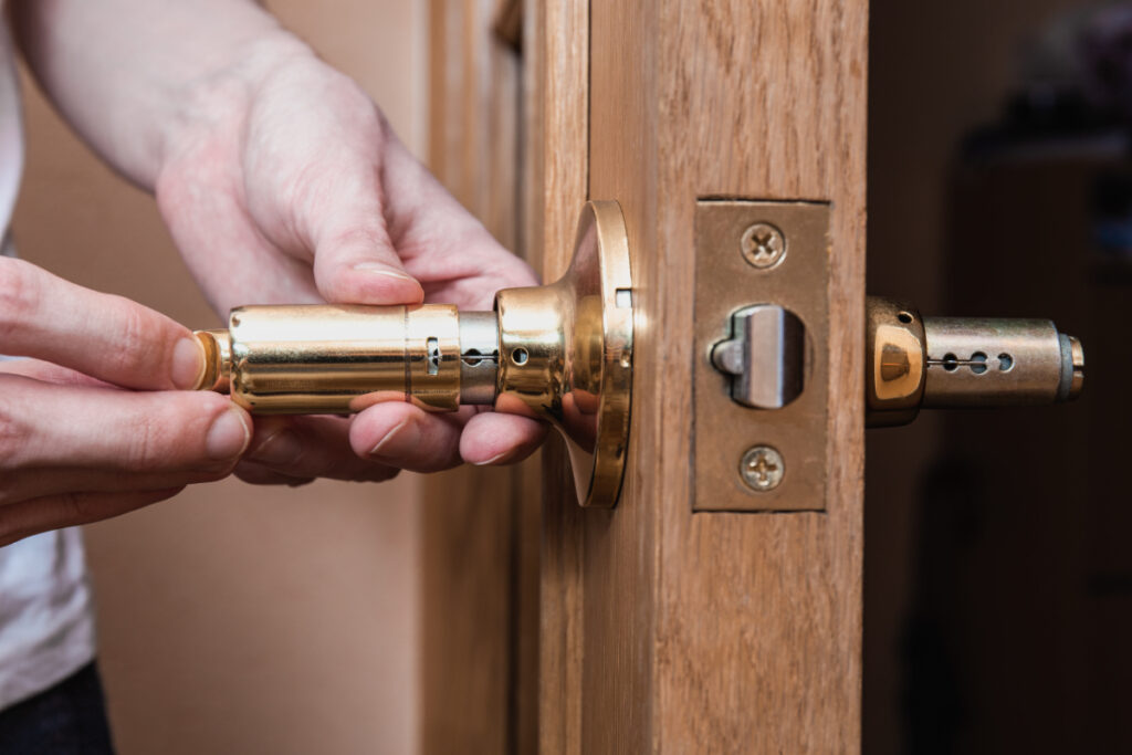 Person replacing a brass door lock cylinder.