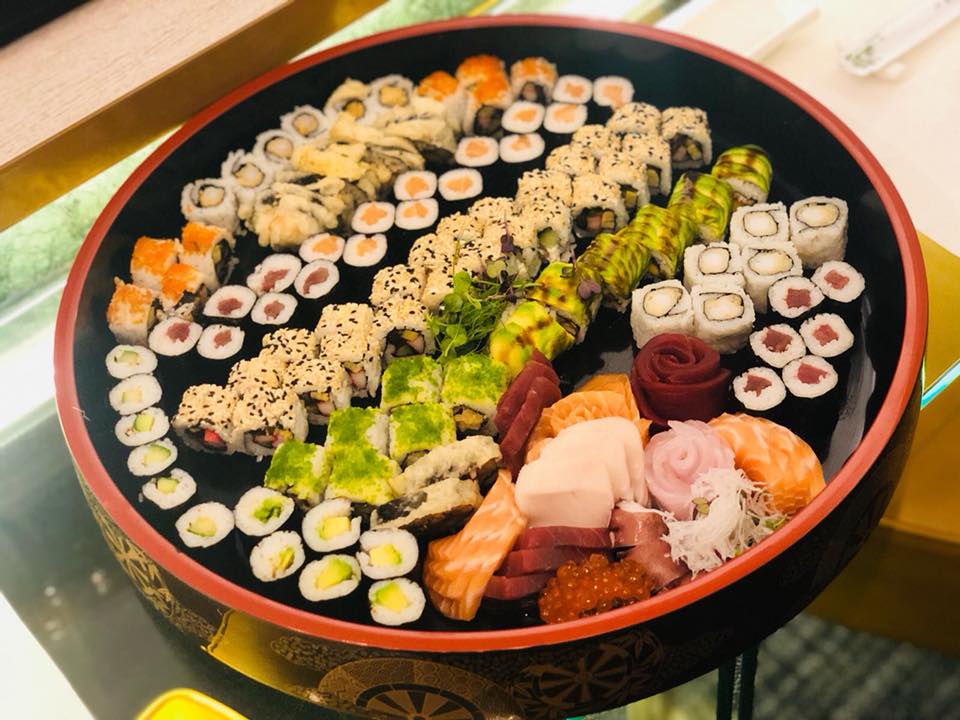 Round sushi platter with assorted rolls and sashimi.